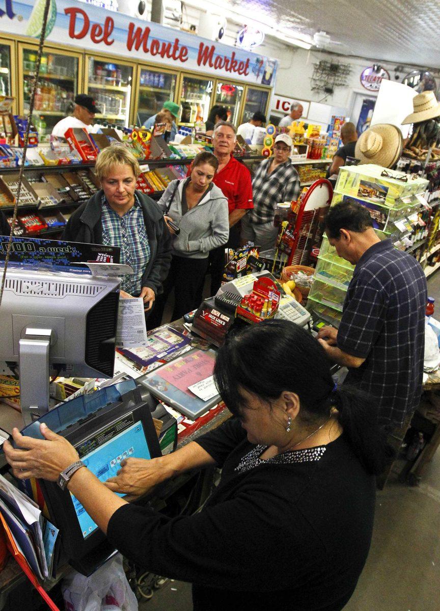 Anita Ganatra, front, and Keith Ganatra, far right, owners of the Del Monte Market, help the long line of customers inside their store waiting to buy Powerball lottery tickets Wednesday, Nov. 28, 2012, in Phoenix. There has been no Powerball winner since Oct. 6, and the jackpot has already reached a record level for the game of over $550 million.(AP Photo/Ross D. Franklin)