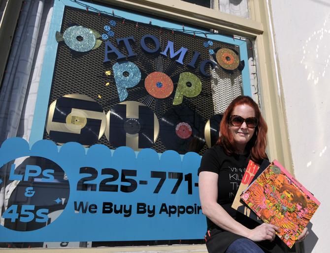 Atomic Pop Shop owner Kerry Beary shows Wednesday, Jan. 23, 2013 some of her favorite albums in front of the store on Government St.
 