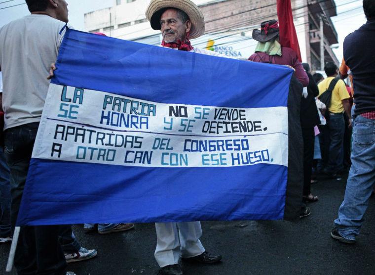 Opposition supporters demonstrate against recent laws approved by congress outside parliament in Tegucigalpa, Honduras, Thursday Jan. 24, 2013. Honduras has been on the brink of bankruptcy for months, as lawmakers put off passing a government budget necessary to pay for basic government services. The country is also grappling with $5 billion in foreign debt, the biggest hole in its history and equivalent to last year&#8217;s entire government budget. The sign reads in Spanish '"The nation is not for sale, you honor it and you defend it. Congressmen with no country, go to a different dog with that bone."(AP Photo/Alberto Arce)
 