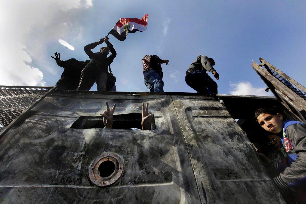 Egyptian protesters celebrate the capture of a state security armored vehicle that demonstrators commandeered during clashes with security forces and brought to Tahrir Square in Cairo, Egypt, Tuesday, Jan. 29, 2013. Egypt&#8217;s army chief warned Tuesday of the &#8220;the collapse of the state&#8221; if the political crisis roiling the nation for nearly a week continues, but said the armed forces will respect the right of Egyptians to protest. A protester waves the Egyptian national flag. (AP Photo/Amr Nabil)