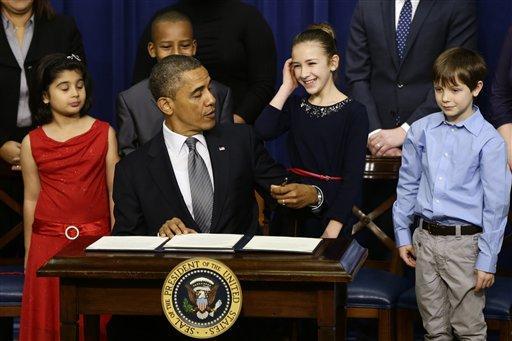 From left to right: Hinna Zeejah, 8, Taejah Goode, 10, Julia Stokes, 11, and Grant Fritz, 8, who wrote letters to President Barack Obama about the school shooting in Newtown, Conn., watch as the president jokes about being left handed as he signs executive orders outlining proposals to reduce gun violence, Wednesday, Jan. 16, 2013, in the South Court Auditorium at the White House in Washington. (AP Photo/Charles Dharapak)
 