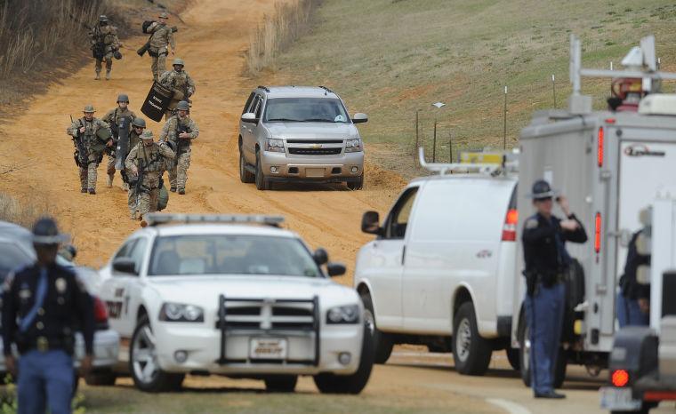 Heavily armed men move away from the suspects home at the scene of a Dale County hostage scene in Midland City, Ala. on Wednesday Jan. 30, 2013. Authorities were locked in a standoff Wednesday with a gunman authorities say on Tuesday intercepted a school bus, killed the driver, snatched a 6-year-old boy and retreated into a bunker at his home in Alabama. (AP Photo/Montgomery Advertiser, Mickey Welsh) NO SALES
 