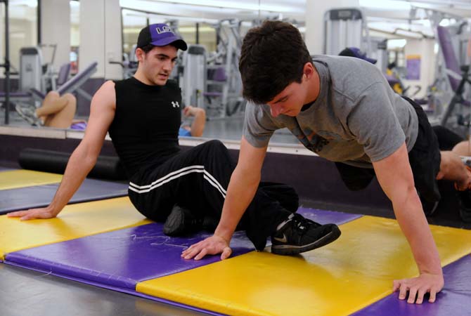 Accounting sophomore Jared Arceneaux, left, helps fellow accounting sophomore and first cousin Garrett Arceneaux, right, with his push-up set in the UREC on January 13, 2013. They both have the New Year's resolution to meet the Navy Seal's fitness requirements just to see if they can do it.
 