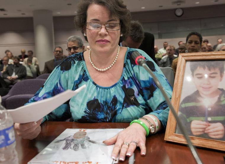 Veronique Pozner places her hand next to artwork made by her son Noah's before testifying before a hearing of a legislative subcommittee reviewing gun laws at the Legislative Office Building in Hartford, Conn., Monday, Jan. 28, 2013. Pozner, whose son Noah was killed in the Sandy Hook School shooting, told lawmakers about dropping off two of her daughters at the new Sandy Hook Elementary School in Monroe, and then visiting her son's grave, just five minutes away, to bring a teddy bear. (AP Photo/Jessica Hill)
 