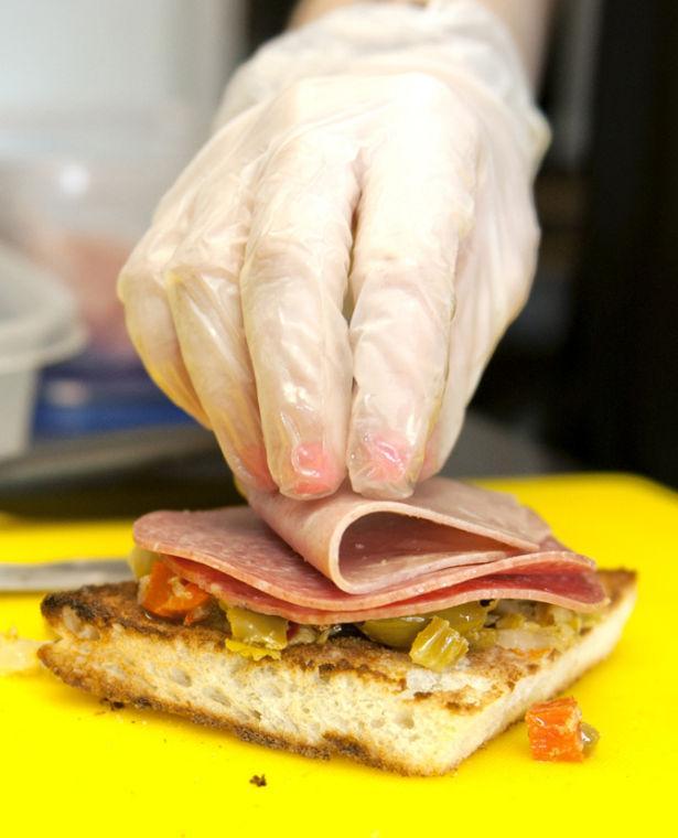 LSU Communication Disorder senior Leigh Ann Town places Saturday, Jan. 26, 2013 one of the three meats on a quarter of a muffaletta from 926-Muff on Congress Blvd. The 926-Muff is open 7 days a week from 11am-7pm and delivers to LSU.
 