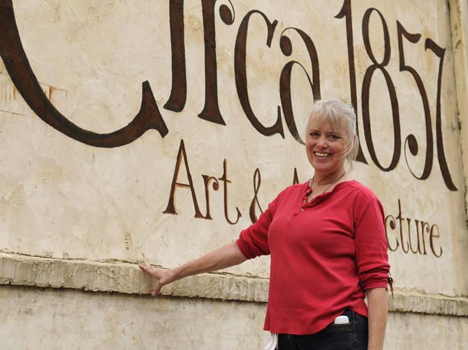 Sally Conklin, the owner of Circa 1857, smiles in front of the hand-painted shop name on the side of the Circa 1857 building on Government St. on Jan. 28, 2013.
 