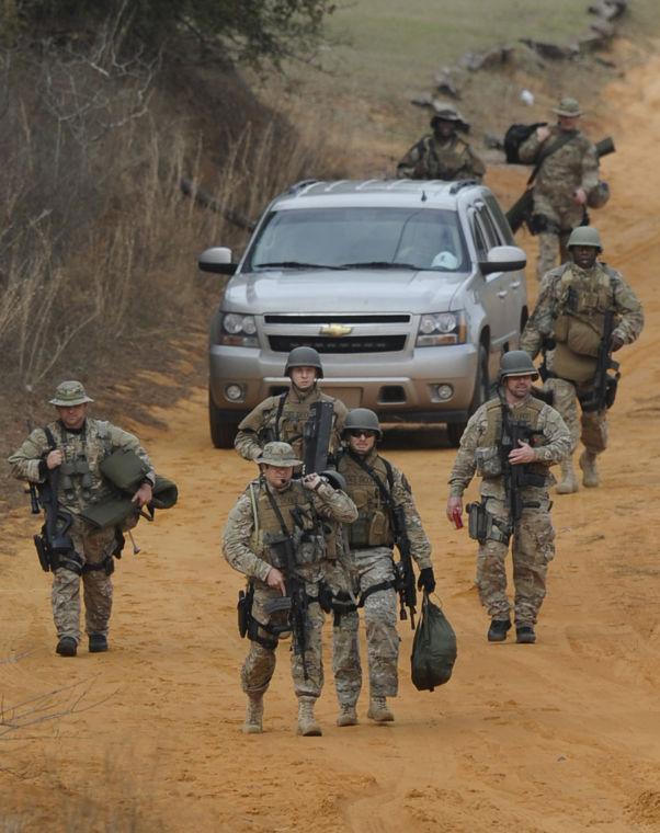 Heavily armed men come back down the hill from the direction of the suspect's home at the Dale County hostage scene near Midland City, Ala. on Wednesday Jan. 30, 2013. Police SWAT teams and hostage negotiators were locked in a standoff Wednesday with a gunman authorities say intercepted a school bus, killed the driver, snatched a 6-year-old boy and retreated into a bunker at his home. (AP Photo/Montgomery Advertiser, Mickey Welsh) NO SALES
 