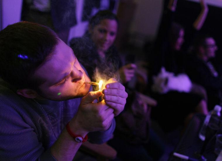 A man smokes marijuana on the official opening night of Club 64, a marijuana-specific social club, where a New Year's Eve party was held, in Denver, Monday Dec. 31, 2012. On Election Day, Nov. 6, 2012, a plurality of Coloradans voted in favor of Proposition 64 to legalize recreational marijuana. (AP Photo/Brennan Linsley)