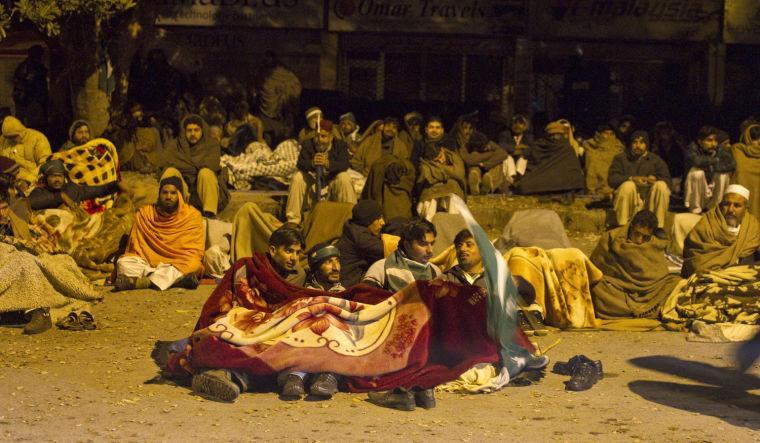 Supporters of Pakistani Sunni Muslim cleric Tahir-ul-Qadri, rest in a cold weather at an anti government rally in Islamabad, Pakistan Tuesday, Jan. 15, 2013. Thousands of Pakistanis fed up with political leaders they say are corrupt and indifferent rallied in the Pakistani capital Tuesday, as the fiery cleric who organized the rally called for the government to resign and for his followers to remain on the streets until then. (AP Photo/Anjum Naveed)
 