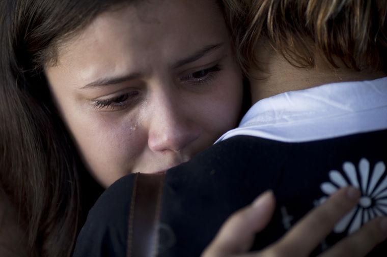 A woman shed tears as she is embraced during the funeral of Gustavo Goncalves, the most recent victim of the Kiss nightclub fatal fire, raising the death toll to 235, in Santa Maria, Brazil, Wednesday, Jan. 30, 2013. A fast-moving fire roared through the crowded, windowless nightclub in this southern Brazilian city early Sunday. The first funeral services were held Monday for the victims. Most of the dead were college students 18 to 21 years old, but they also included some minors. (AP Photo/Felipe Dana)
 