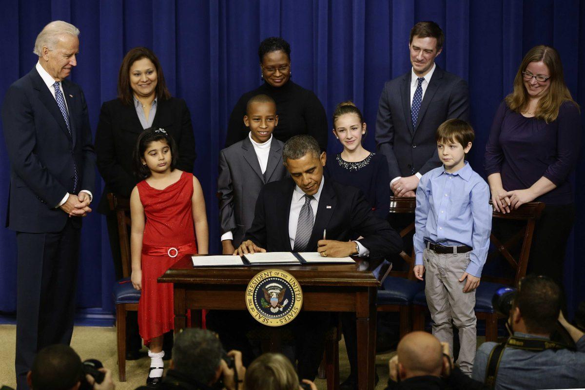 President Barack Obama, accompanied by Vice President Joe Biden, and children who wrote the president about gun violence following last month's shooting at an elementary school in Newtown, Conn., signs executive orders to reduce gun violence, Wednesday, Jan. 16, 2013, in the South Court Auditorium at the White House in Washington. From left are: Biden Hinna Zeejah, 8, and Nadia Zeejah, Hinna&#8217;s mother, Taejah Goode, 10, and Kimberly Graves, Taejah&#8217;s mother, Julia Stokes, 11, and Dr. Theophil Stokes, Julia&#8217;s father, and Grant Fritz, 8, (AP Photo/Charles Dharapak)