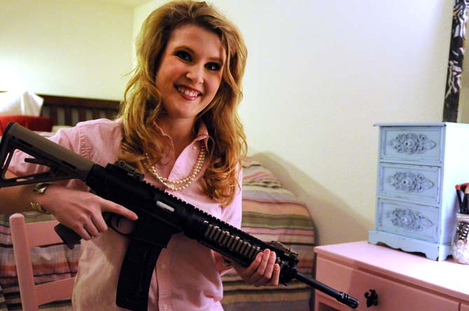 Arielle Sutton, a junior agricultural business major, holds her Smith &amp; Wesson&#8217;s M&amp;P 15-22 rifle in her Tiger Manor apartment on Jan. 14, 2013.
 