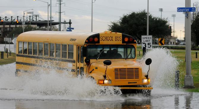 A school bus plows Thursday, Jan. 10, 2013 through the flood waters on Burbank Drive and Gourrier Avenue.
 