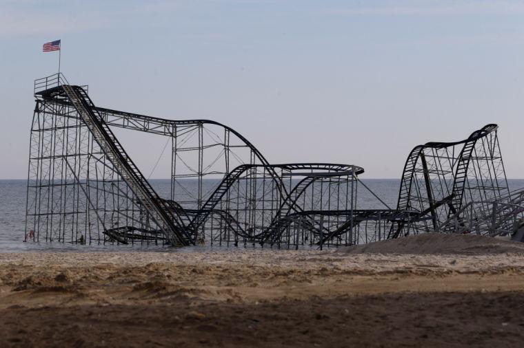 A flag waves from the top of the Jet Star Roller Coaster, Tuesday, Jan. 8, 2013 in Seaside Heights, N.J. Police detained a man who allegedly placed the flag after climbing on the roller coaster, which has been sitting on the ocean after part of the Funtown Pier was destroyed during Superstorm Sandy. Officials say the man came down from the top of the coaster and jumped into a police boat. He was handcuffed, walked through the surf and was escorted to a police car on the beach in Seaside Heights. (AP Photo/Julio Cortez)
 