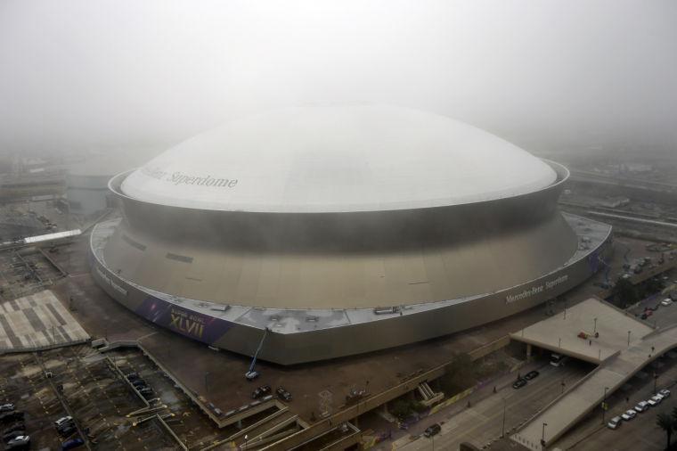 In this Jan. 15, 2013, photo, workers put up signage for the upcoming Super Bowl on the Superdome in New Orleans. With the Super Bowl in New Orleans Feb. 3 and Mardi Gras falling just nine days later, the city is gearing up for a massive celebration and influx of tourists that locals are calling "Super Gras." (AP Photo/Gerald Herbert)