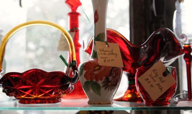 A few pieces of ruby red glassware and floral painted vase sit on a shelf illuminated by the sun in the Circa 1857 shop on Jan. 28, 2013.
 