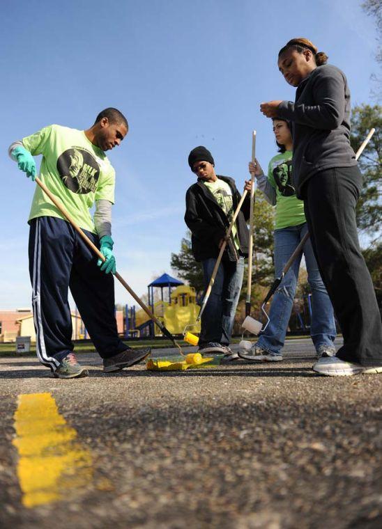 Microbiology senior Charles Lewis (far left), pre-art sophomore Nicholas Belson (middle left), animal-dairy-poultry sophomore Natalia Arango (middle right) and computer science sophomore Teryn Thornton (far right) prepare to paint stripes on a basketball court Monday Jan. 21, 2013 outside of McKinley High School.
 