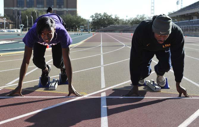 Sophomore sprinter Aaron Ernest (right) and senior sprinter Kimberlyn Duncan (left) practice at the Bernie Moore Track Stadium on Jan. 30, 2013.
 