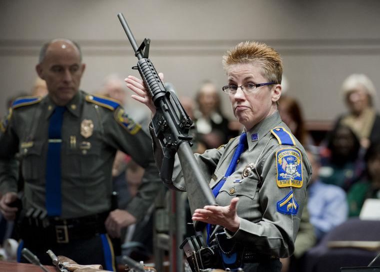 Firearms Training Unit Detective Barbara J. Mattson of the Connecticut State Police holds up a Bushmaster AR-15 rifle, the same make and model of gun used by Adam Lanza in the Sandy Hook School shooting, for a demonstration during a hearing of a legislative subcommittee reviewing gun laws, at the Legislative Office Building in Hartford, Conn., Monday, Jan. 28, 2013. The parents of children killed in the Newtown school shooting called for better enforcement of gun laws Monday at the legislative hearing. (AP Photo/Jessica Hill)
 