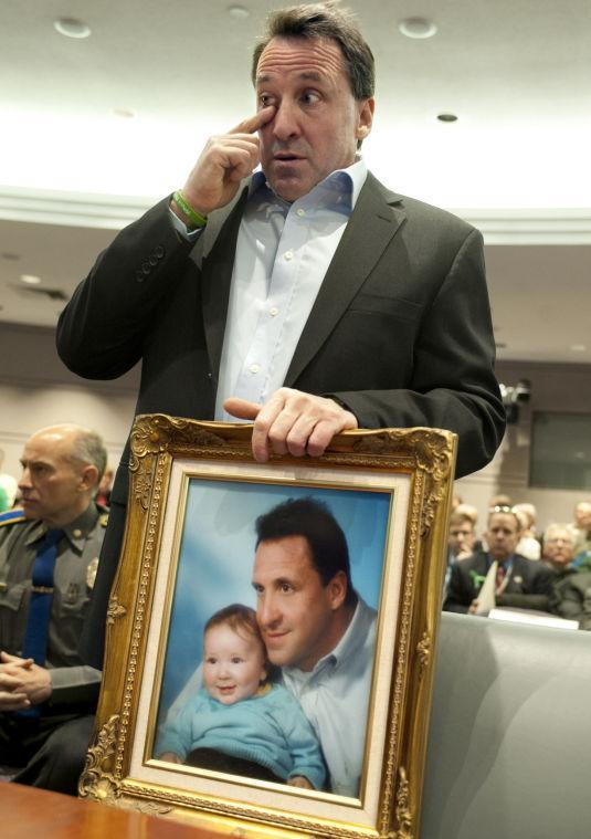 Neil Heslin, holding a picture of himself with his son Jesse, wipes his eye before testifying at a hearing in the Legislative Office Building in Hartford, Conn., Monday, Jan. 28, 2013. Heslin, whose 6-year-old son Jesse Lewis was one of the 20 first-graders killed in the Dec. 14 Newtown massacre, told a legislative subcommittee reviewing gun laws that there is no need for such weapons in homes or on the streets. (AP Photo/Jessica Hill)
 