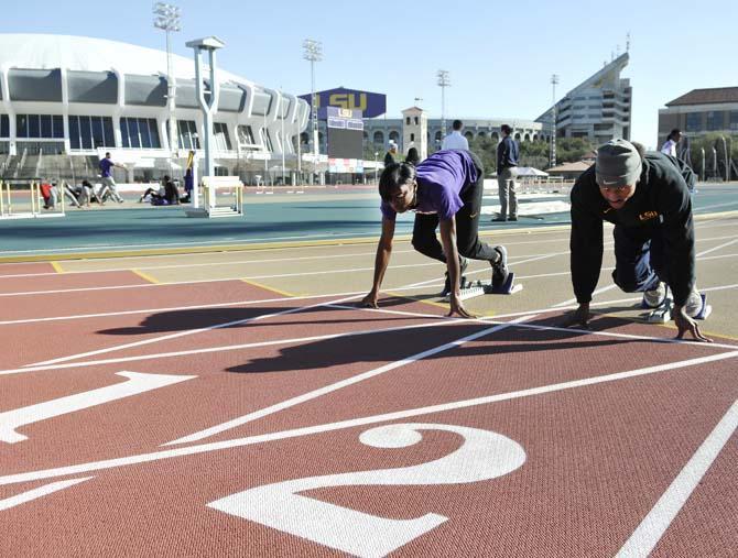 Sophomore sprinter Aaron Ernest (right) and senior sprinter Kimberlyn Duncan (left) practice at the Bernie Moore Track Stadium on Jan. 30, 2013.
 