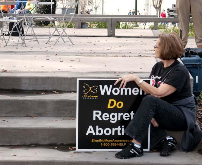 A pro-life protester sits Saturday, Jan. 12, as she listens to speakers at the Old State Capitol in downtown Baton Rouge.
 