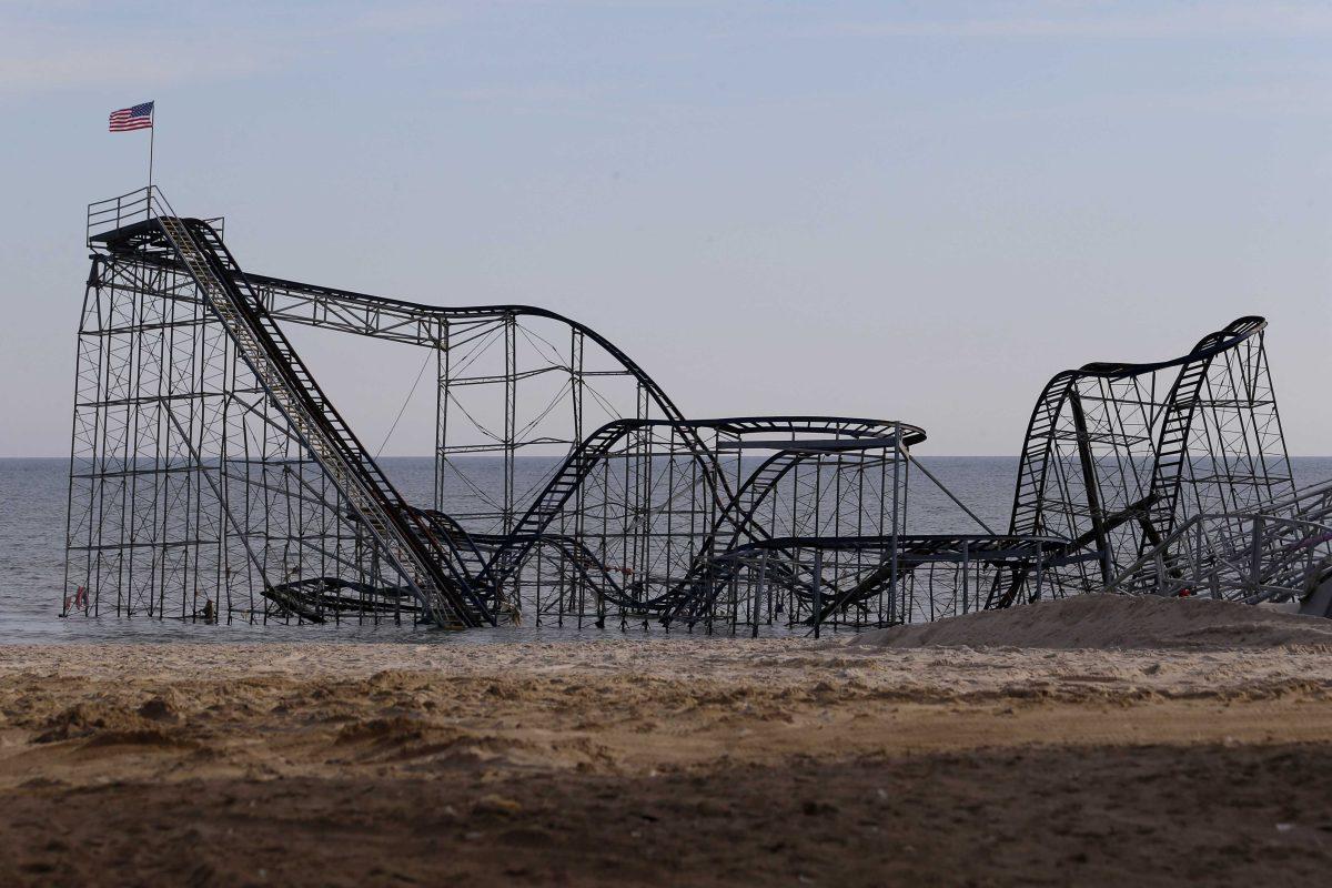 A flag waves from the top of the Jet Star Roller Coaster, Tuesday, Jan. 8, 2013 in Seaside Heights, N.J. Police detained a man who allegedly placed the flag after climbing on the roller coaster, which has been sitting on the ocean after part of the Funtown Pier was destroyed during Superstorm Sandy. Officials say the man came down from the top of the coaster and jumped into a police boat. He was handcuffed, walked through the surf and was escorted to a police car on the beach in Seaside Heights. (AP Photo/Julio Cortez)