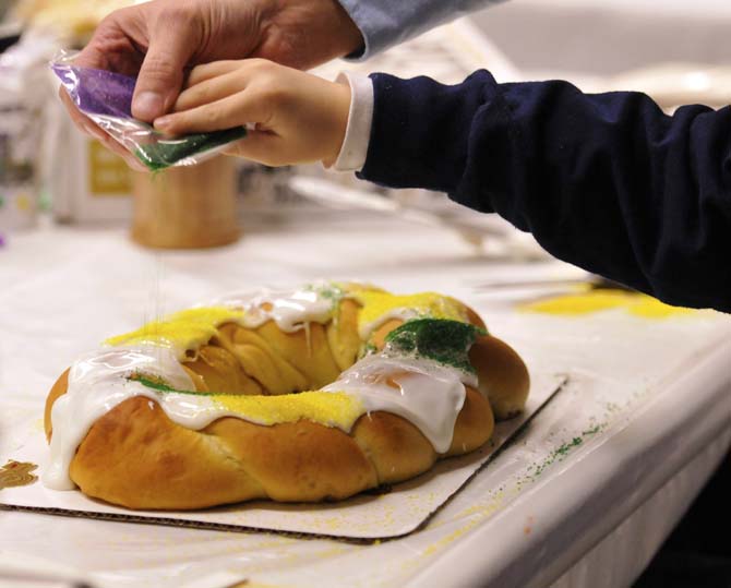 Felix Sherman Jr., the owner of Ambrosia Bakery, helps 7-year-old Paul Pittman pour sprinkles on a king cake as part of a king cake demonstration at the LSU Museum of Art on January 17, 2012.
 