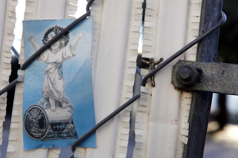 A photo and a milagro are attached to the fence at the entrance of the Routh Street Women's Clinic during the Roe Memorial Rosary/Jericho Walk to mark the 40th anniversary of the 1973 Roe v. Wade decision that legalized abortion, in Dallas on Saturday, Jan. 19, 2013. (AP Photo/The Dallas Morning News, Lara Solt)
 