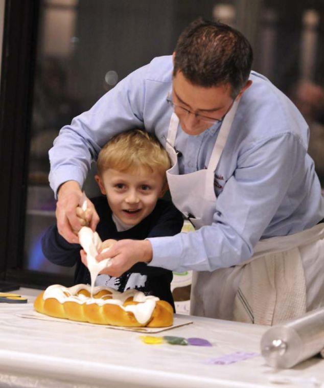 Felix Sherman Jr., the owner of Ambrosia Bakery, helps 7-year-old Paul Pittman ice a king cake as part of a king cake demonstration at the LSU Museum of Art on January 17, 2012.
 