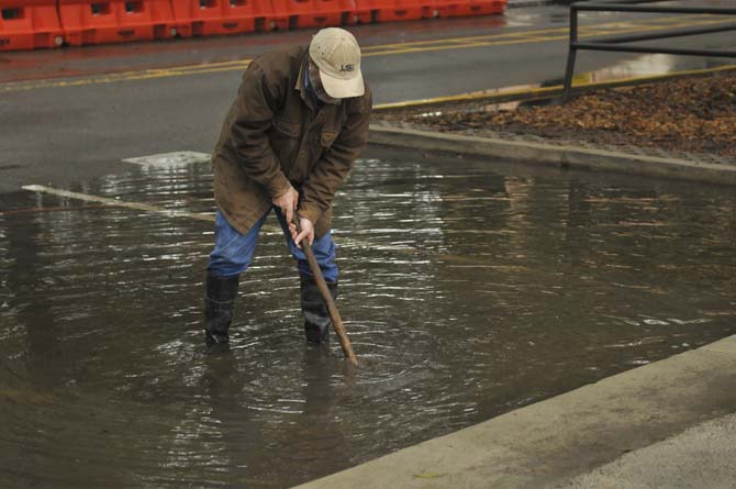 A Facility Services worker unclogs a drain January 9, 2013 after a day and a half of nonstop rain on campus.
 