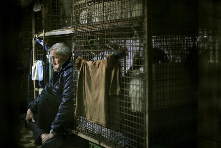 In this Jan. 25, 2013 photo, 77-year-old Yeung Ying Biu sits inside his 1.5 square meter (16 square feet) cage, which he calls home, in Hong Kong. For many of the richest people in Hong Kong, one of Asia's wealthiest cities, home is a mansion with an expansive view from the heights of Victoria Peak. For some of the poorest, home is a metal cage. Some 100,000 people in the former British colony live in what's known as inadequate housing, according to the Society for Community Organization, a social welfare group. (AP Photo/Vincent Yu)
 