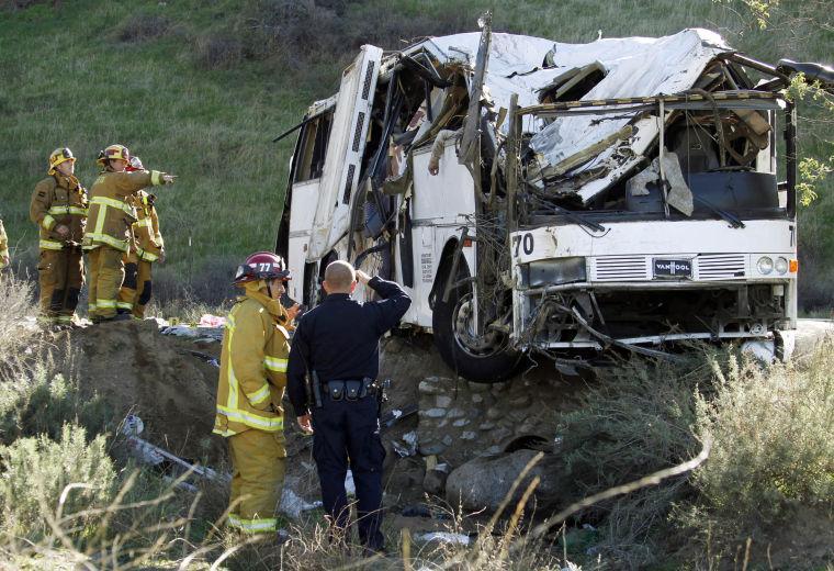 EDITORS NOTE GRAPHIC CONTENT - Firefighters and a California Highway Patrol officer survey the scene of an accident where at least eight people were killed and 38 people were injured after a tour bus, left, carrying a group from Tijuana, Mexico crashed with two other vehicles just north of Yucaipa, Calif., Sunday, Feb. 3, 2013. The arm of a deceased victim is seen at top center. (AP Photo/Reed Saxon)
 