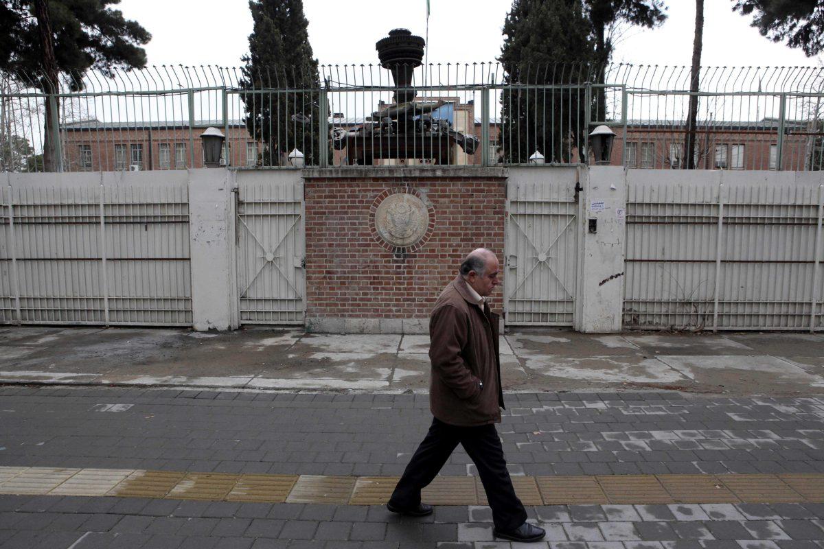 A man walks past the main gate of the former U.S. Embassy in Tehran, where militant Iranian students seized on Nov. 4, 1979, believing the embassy to be a center of plots against Iran, and then held 52 Americans hostage for 444 days, in Iran, Monday, Feb. 25, 2013. Iran's state TV dismissed the Oscar-winning film "Argo" on Monday as an "advertisement for the CIA" and some Iranians called the award a political statement by America for its unflattering portrayal of the aftermath of the 1979 Islamic Revolution. Wreckage of a US helicopter which crashed in 1980 during a failed US mission to free 52 American hostages held at the US embassy is placed on the gate. (AP Photo/Vahid Salemi)