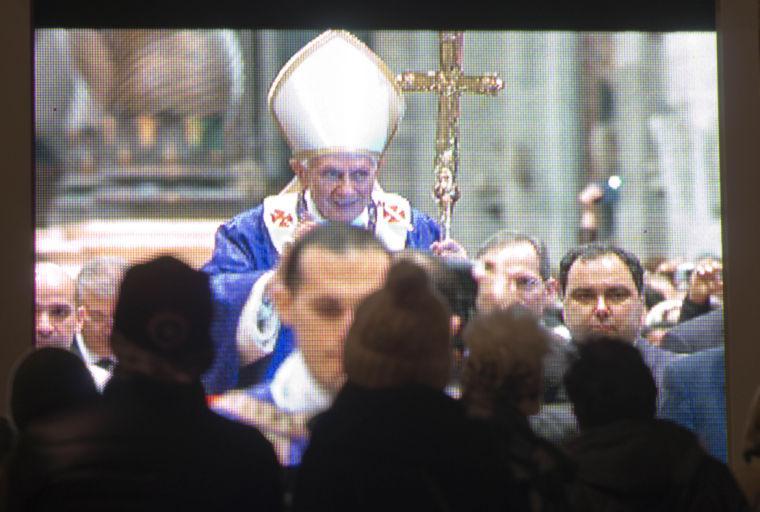 Faithful watch a giant screen placed under the statue of St. Peter, in St. Peter's Square at the Vatican, showing Pope Benedict XVI celebrating the Ash Wednesday mass in St. Peter's Basilica, Wednesday, Feb. 13, 2013. With a few words in Latin, Pope Benedict XVI did what no pope has done in more than half a millennium, stunning the world by announcing his resignation Monday and leaving the already troubled Catholic Church to replace the leader of its 1 billion followers by Easter. (AP Photo/Domenico Stinellis)
 