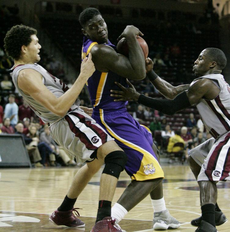 LSU's Johnny O'Bryant III, center, drives for the basket as South Carolina Michael Carrera, left, and Bruce Ellington, right, tries to block during the second half of their NCAA college basketball game on Thursday, Feb. 14, 2013, in Columbia, S.C. O'Bryant III scored 30 total points as they defeated South Carolina 64-46.( AP Photo/Mary Ann Chastain)
 