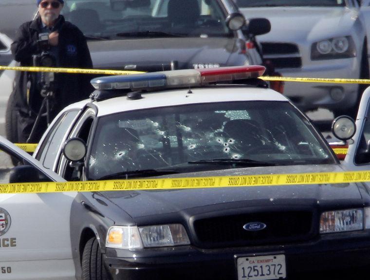 Police tape surrounds a bullet-damaged Los Angeles Police vehicle on Thursday Feb. 7, 2013 in Corona, Calif. Former Los Angeles police officer Christopher Dorner is suspected if shooting at two LAPD officers in the vehicle who were sent to Corona to protect someone Dorner threatened in a rambling online manifesto. One officer's head was grazed by a bullet. Thousands of police officers throughout Southern California and Nevada hunted Thursday for Dorner, who was angry over his firing and began a deadly shooting rampage that he warned in an online posting would target those on the force who wronged him. (AP Photo/Nick Ut)
 