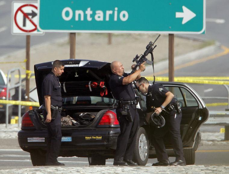 A Los Angeles Police officer checks his weapon at the site of a shooting Thursday Feb. 7, 2013 in Corona, Calif. Christopher Dorner is suspected of shooting two LAPD officers who were sent to Corona to protect someone Dorner threatened in a rambling online manifesto. Thousands of police officers throughout Southern California and Nevada hunted Thursday for Dorner, a former Los Angeles officer who was angry over his firing and began a deadly shooting rampage that he warned in an online posting would target those on the force who wronged him(AP Photo/Nick Ut)
 