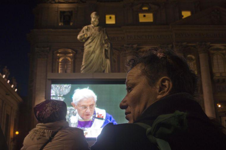 Faithful watch a giant screen placed under the statue of St. Peter, in St. Peter's Square at the Vatican, showing Pope Benedict XVI celebrating the Ash Wednesday mass in St. Peter's Basilica, Wednesday, Feb. 13, 2013. With a few words in Latin, Pope Benedict XVI did what no pope has done in more than half a millennium, stunning the world by announcing his resignation Monday and leaving the already troubled Catholic Church to replace the leader of its 1 billion followers by Easter. (AP Photo/Domenico Stinellis)
 