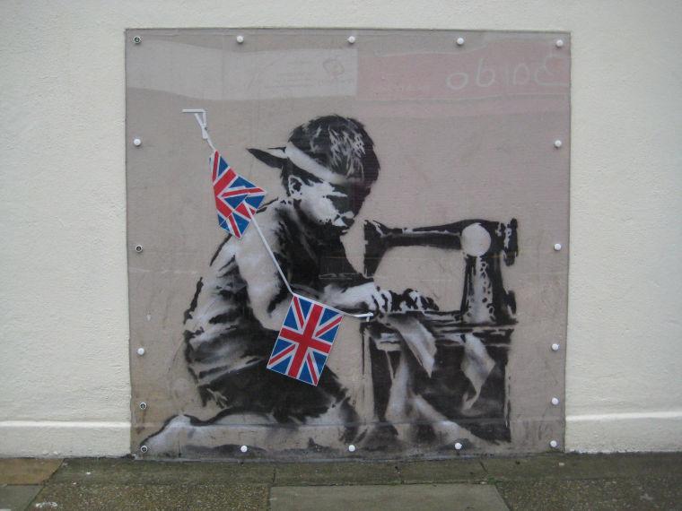 This is an undated image of an art work from British artist Banksy made available by Haringey Council Wednesday Feb. 20, 2013. The stencil by the famed, secretive graffiti artist of a young boy sewing Union Jack bunting on an antique sewing machine appeared on the side of a north London bargain store last May. Soon the gritty Turnpike Lane area was drawing art lovers keen to see Banksy's typically cheeky take on the Diamond Jubilee celebrations of Queen Elizabeth II's 60 years on the British throne. Last week it vanished, leaving nothing but a rectangle of exposed brick &#8212; only to reappear on the website of a Miami auction house. Listed as "Slave Labor (Bunting Boy)," it is due to be sold Saturday with an estimated price of between $500,000 and $700,000. (AP Photo/Haringey Council) NO ARCHIVE
 