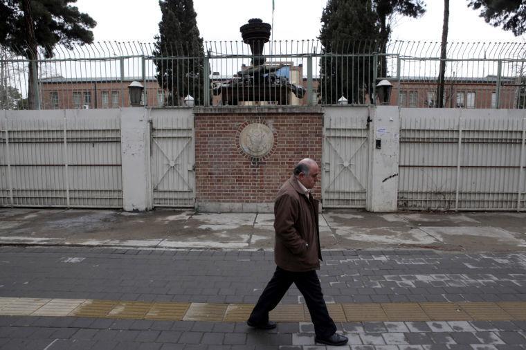 A man walks past the main gate of the former U.S. Embassy in Tehran, where militant Iranian students seized on Nov. 4, 1979, believing the embassy to be a center of plots against Iran, and then held 52 Americans hostage for 444 days, in Iran, Monday, Feb. 25, 2013. Iran's state TV dismissed the Oscar-winning film "Argo" on Monday as an "advertisement for the CIA" and some Iranians called the award a political statement by America for its unflattering portrayal of the aftermath of the 1979 Islamic Revolution. Wreckage of a US helicopter which crashed in 1980 during a failed US mission to free 52 American hostages held at the US embassy is placed on the gate. (AP Photo/Vahid Salemi)
 