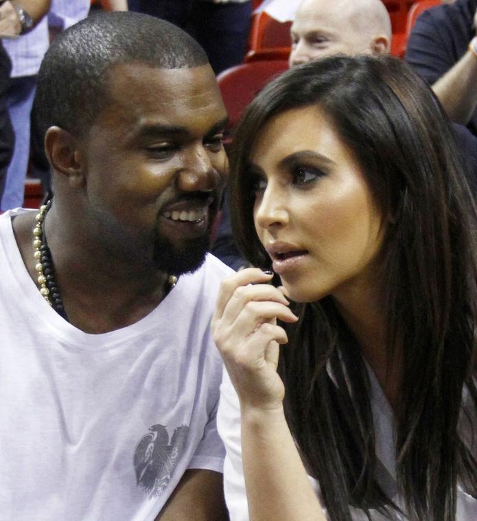 FILE - In this Dec. 6, 2012 file photo singer Kanye West, left, talks to his girlfriend Kim Kardashian before an NBA basketball game between the Miami Heat and the New York Knicks in Miami. Authorities say an airline employee is being investigated for allowing West and Kardashian to bypass a security checkpoint at New York's Kennedy Airport. (AP Photo/Alan Diaz, File)