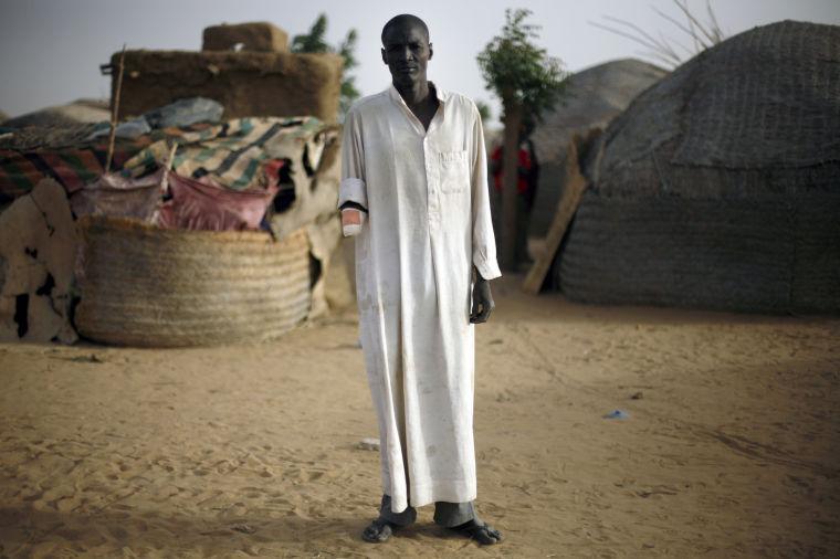 FILE - In this Jan. 31, 2013 file photo, Issa Alzouma, 39, poses in front of his home in Gao, northern Mali, Thursday, Jan. 31, 2013. Alzouma's arm was amputated by Islamist radicals on Dec. 21, 2012, after an Islamic tribunal charged him with spying. Alzouma, a father of three, denied the charges, and said he was just changing the faulty plug on his motorcycle's engine alongside the road. The extremists fled the city Saturday as French, Chadian and Nigerian troops arrived, ending 10 months of radical Islamic control over the city. But the intervention came too late for Alzouma and the other men who lost their hands and probably their livelihoods, too, when the militants carried out amputations as punishments for theft and other alleged crimes under their strict interpretation of Shariah, or Islamic law. (AP Photo/Jerome Delay, File)
 