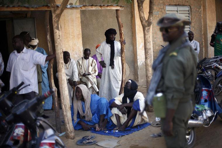 Malian men listen to soldiers in Gao, northern Mali, Tuesday Feb. 5, 2013. Troops from France and Chad moved into Kidal in an effort to secure the strategic north Malian city, a French official said Tuesday, as the international force put further pressure on the Islamic extremists to push them out of their last major bastion of control in the north.(AP Photo/Jerome Delay)
 