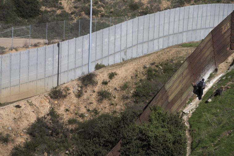 A man walks along the Mexico side of the old border fence as the newer fence sits in the distance Tuesday, Jan. 29, 2013, in Tijuana, Mexico. The President on Tuesday praised bipartisan efforts to overhaul the nation's immigration laws, welcoming "a genuine desire" to tackle a famously snarled system that has been stalled for almost two decades. (AP Photo/Gregory Bull)
 