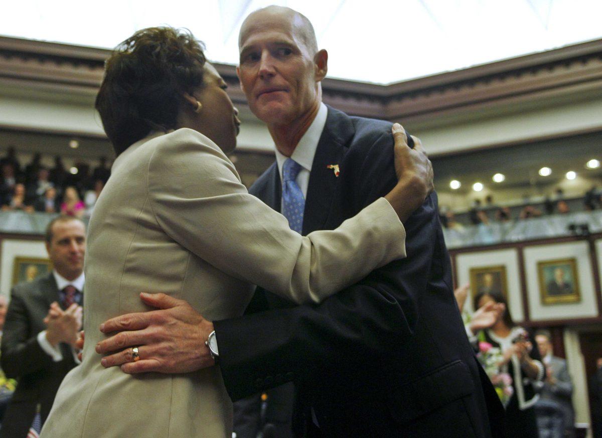 In this Tuesday, March 5, 2013 file photo, Florida Lt. Gov. Jennifer Carroll and Gov. Rick Scott embrace prior to his State of the State speech in the Florida House of Representatives in Tallahassee, Fla. Carroll resigned and nearly 60 other people were charged in a widening scandal of a purported veterans charity that authorities said Wednesday, March 13, 2013 was a $300 million front for illegal gambling. (AP Photo/Phil Sears, File)