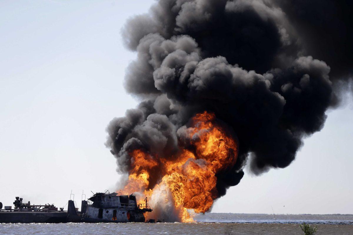 A fire still burns after a tugboat and barge hit a gas pipeline yesterday evening in Perot Bay in Lafourche Parish, La., Wednesday, March 13, 2013. (AP Photo/Gerald Herbert)