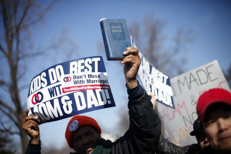 A demonstrator holds a bible while marching outside the Supreme Court in Washington, Tuesday, March 26, 2013, as the court heard arguments on California's voter approved ban on same-sex marriage, Proposition 8. The Supreme Court waded into the fight over same-sex marriage Tuesday, at a time when public opinion is shifting rapidly in favor of permitting gay and lesbian couples to wed, but 40 states don't allow it. (AP Photo/Pablo Martinez Monsivais)
 