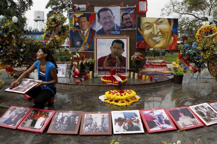 A woman wipes photos of late President Hugo Chavez at a makeshift altar set in his honor at the main square of Sabaneta, western Venezuela on Saturday, March 9, 2013. Chavez, who died of cancer on March 5, 2013 was born in Sabaneta. His former home has been turned into the local headquarters of the United Socialist Party of Venezuela, PSUV. (AP Photo/Esteban Felix)
 