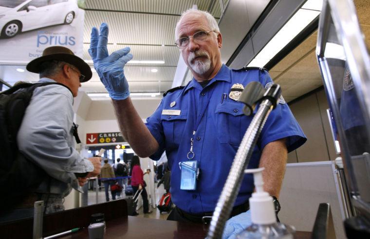 FILE - In this Jan. 4, 2010 file photo, TSA officer Robert Howard signals an airline passenger forward at a security check-point at Seattle-Tacoma International Airport in SeaTac, Wash. Flight attendants, pilots, federal air marshals and even insurance companies are part of a growing backlash to the Transportation Security Administration&#8217;s new policy allowing passengers to carry small knives and sports equipment like souvenir baseball bats and golf clubs onto planes. (AP Photo/Elaine Thompson, File)
 